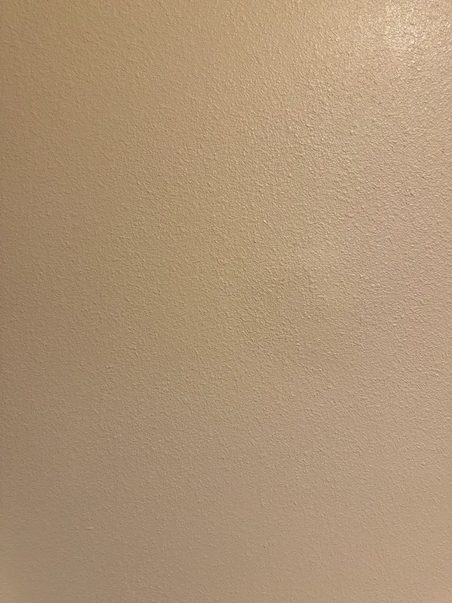 Close-up of a repaired interior wall with a painted, textured surface