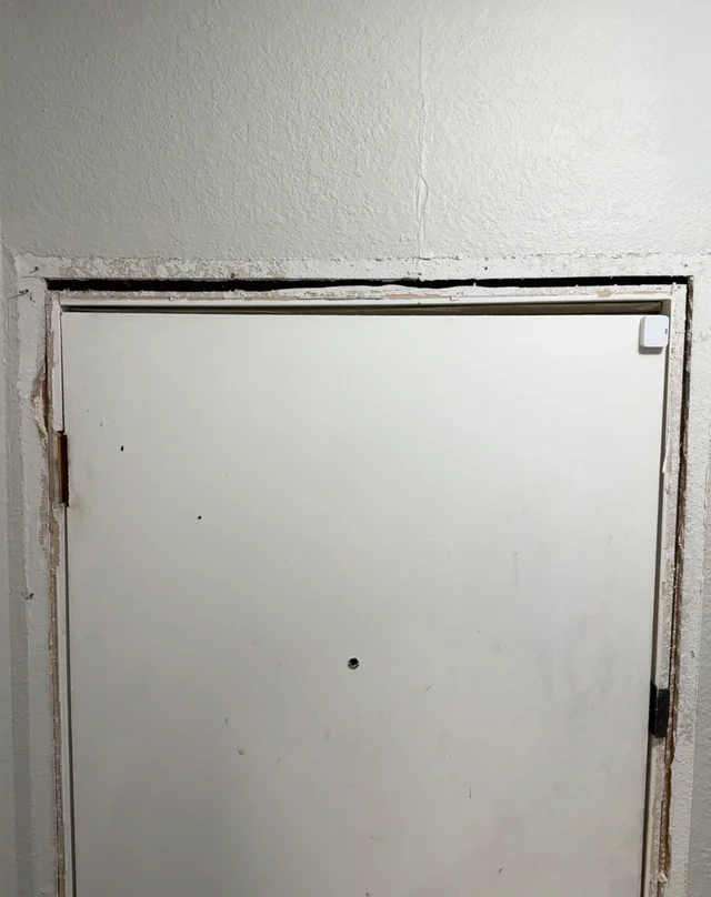 Inside of an exterior doorway with trim removed and an exposed gap around the frame