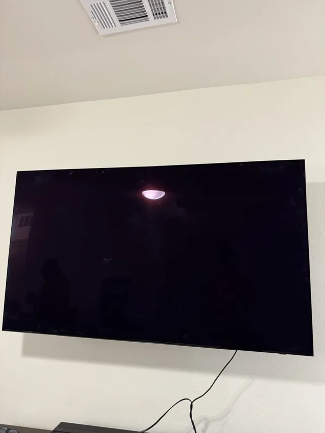 TV mounted on an interior wall, with its cable visible below